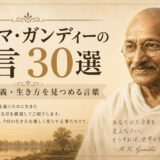 糸車とインドの風景を配したマハトマ・ガンディーの肖像風ビジュアルによる「名言30選」のアイキャッチ画像