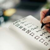 ノートのチェック欄に印をつけ、小さな行動の進捗を記録する手元