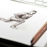 白い紙と二本の鉛筆が置かれた作業途中を思わせる机上