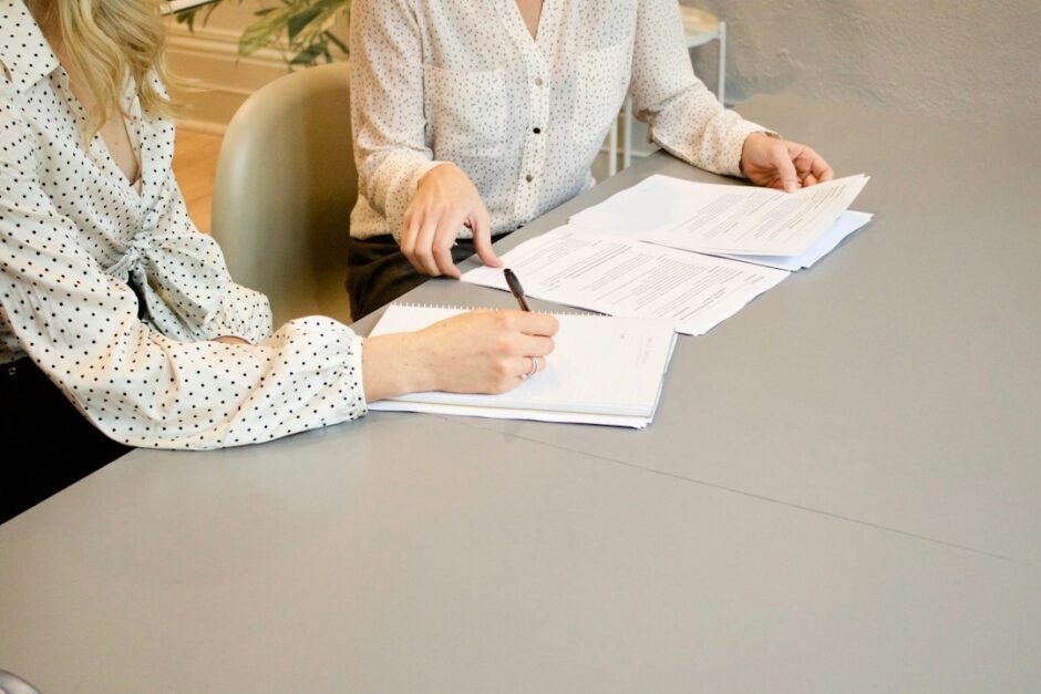 書面に署名する人と、内容を確認する相手の手。約束や合意を象徴するイメージ写真