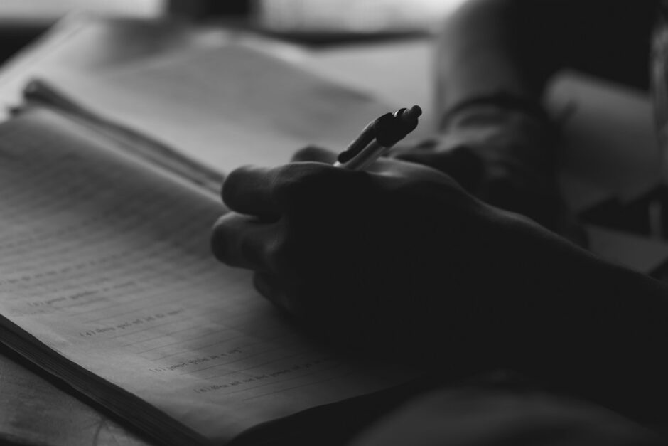 ノートにペンで書き込む手元。年齢を重ねても続く学びと日々の記録を象徴する写真