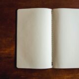 開いたノートとペンのある机。罪悪感を整理し、次の行動を考えるイメージ